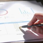 person pointing his black pen on the paper